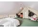 An attic bedroom with an angled ceiling contains a bed, shelving, an office chair, and hanging clothes at 600 Lake Overlook Dr, Canton, GA 30114