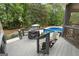 Backyard deck with grill overlooking a beautiful pool surrounded by lush landscaping and mature trees at 130 Allie Drive, Mcdonough, GA 30252