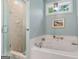 Bathroom featuring a shower, a bathtub, white tile, with a framed painting, seashells, and a bright window at 130 Allie Drive, Mcdonough, GA 30252