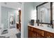 Bathroom with wooden cabinets, a white countertop, a large mirror, and a view of an adjoining room at 130 Allie Drive, Mcdonough, GA 30252