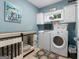Well-lit laundry room with blue walls, front load washer and dryer, and custom dog crate at 130 Allie Drive, Mcdonough, GA 30252