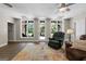 Bright living room with hardwood flooring, a ceiling fan, with three large windows with views of a backyard at 130 Allie Drive, Mcdonough, GA 30252