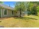 Backyard of a single-story home with mature trees and grassy area at 1404 Meadowind Court Sw, Conyers, GA 30094