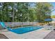 In-ground pool with slide, fencing, patio furniture and blue umbrellas surrounded by mature trees at 212 Warrenton Dr, Douglasville, GA 30134