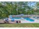 Backyard pool area featuring a pool, slide, tables, chairs, wood deck, lounge chairs and partial fencing at 212 Warrenton Dr, Douglasville, GA 30134