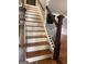 Staircase with stained wood treads, white risers, and decorative black iron railings at 1055 Worthington Hills Dr, Roswell, GA 30076