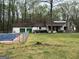 View of pool area and back exterior of the home surrounded by trees in a large yard at 2497 Old Jackson Rd, Locust Grove, GA 30248