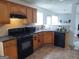 Kitchen with wood cabinets, black appliances, and tile flooring at 11950 Markham Way, Hampton, GA 30228