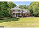 Elegant brick home with a two-story porch, landscaped yard, and mature trees at 218 Woodruff Way, Peachtree City, GA 30269