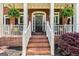 Charming brick home featuring a welcoming front porch with rocking chairs, hanging ferns, and a decorative wreath at 218 Woodruff Way, Peachtree City, GA 30269