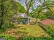 Backyard view featuring a well-maintained lawn, mature trees providing shade, and partial view of the home's rear facade at 1128 Milstead Ne Ave, Conyers, GA 30012