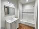 Bathroom featuring a vanity with a mirror, a tiled shower with a built-in shelf, and hardwood floors at 1128 Milstead Ne Ave, Conyers, GA 30012