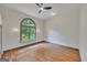 Spacious bedroom with hardwood floors, ceiling fan, wainscoting, and a large arched window with natural light at 1128 Milstead Ne Ave, Conyers, GA 30012