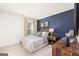 Stylish bedroom featuring a bed with striped bedding, a blue accent wall, and wooden furniture at 560 Whitman Ln # 2016, Stockbridge, GA 30281