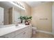 Bathroom featuring a large vanity, well-lit mirror, neutral tile flooring, and green decorative foliage at 3192 Paces Mill Se Rd, Atlanta, GA 30339