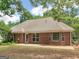 Rear view of brick home showcasing a patio, well-maintained lawn, and serene backyard setting at 1585 Lake Dow Rd, Mcdonough, GA 30252
