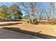 A view of a flat backyard, partially shaded by mature trees and greenery, with space for outdoor activities at 1585 Lake Dow Rd, Mcdonough, GA 30252