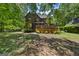 Wood home's backyard has a large deck, surrounded by lush trees and mulch covered ground at 1627 Leguin Mill Rd, Locust Grove, GA 30248