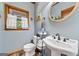 Bathroom features a pedestal sink, oval mirror and wood-trimmed window at 1627 Leguin Mill Rd, Locust Grove, GA 30248
