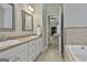 Bathroom featuring a double sink vanity, soaking tub, tile accents, and view into the main bedroom at 465 Crabapple Rd, Fayetteville, GA 30215