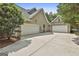 Exterior view of the attached three-car garage with ample parking space and neutral siding at 465 Crabapple Rd, Fayetteville, GA 30215