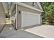 Three-car garage with white doors, neutral siding, and outdoor lighting, offering plenty of space for parking and storage at 465 Crabapple Rd, Fayetteville, GA 30215
