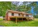 Ranch-style home featuring brick accents, beige siding, and an elevated deck surrounded by mature trees at 428 Cornish Mountain Rd, Oxford, GA 30054