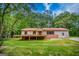 Charming ranch-style home with a red metal roof and an inviting front porch surrounded by lush greenery at 428 Cornish Mountain Rd, Oxford, GA 30054