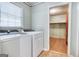 Bright laundry room with modern machines, window, and doorway to storage space at 428 Cornish Mountain Rd, Oxford, GA 30054
