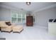 Bedroom sitting area with a cream chaise lounge chair, an armoire, and natural light from the windows at 125 High Bluff Trl, Carrollton, GA 30116