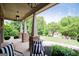 Relaxing front porch featuring elegant stone columns, comfortable striped seating, and picturesque views of the landscaped front yard at 125 High Bluff Trl, Carrollton, GA 30116