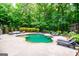 The backyard pool is surrounded by lounge chairs, patio furniture, and tall trees at 125 High Bluff Trl, Carrollton, GA 30116