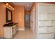 Bathroom featuring an ornate vanity, peach walls, tiled floors, and a view into the shower and hallway at 115 Champion Dr, Carrollton, GA 30116