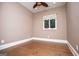 Bedroom featuring hardwood floors, neutral walls, a ceiling fan, and a window, creating a simple and cozy space at 115 Champion Dr, Carrollton, GA 30116