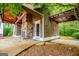 Pool house featuring a stone fireplace, wood siding, covered parking, and an outdoor shower, surrounded by lush trees at 115 Champion Dr, Carrollton, GA 30116