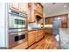 Stainless steel double oven and stovetop in a kitchen featuring custom wood cabinetry and granite countertops at 115 Champion Dr, Carrollton, GA 30116