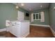 Kitchen area with green walls, hardwood floors, an island with bench seating, and white cabinets, offering cozy charm at 115 Champion Dr, Carrollton, GA 30116