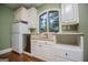 Functional kitchenette featuring white cabinets, stainless steel dishwasher, and hardwood floors, designed for convenience at 115 Champion Dr, Carrollton, GA 30116