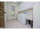 Bright laundry room with tile flooring, white cabinets, utility sink, and modern washer and dryer at 115 Champion Dr, Carrollton, GA 30116