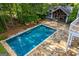 A rectangle pool sits next to a home and near a stone patio in the backyard at 115 Champion Dr, Carrollton, GA 30116
