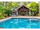Outdoor oasis with a refreshing pool next to a covered structure featuring a stone fireplace and wood detailing at 115 Champion Dr, Carrollton, GA 30116