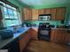 A compact kitchen offers wood cabinets, a black electric stove, dishwasher, and a window with a view at 1711 Mckenzie Dr, Decatur, GA 30032
