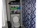 Compact bathroom featuring a toilet, storage shelves, and a blue patterned shower curtain at 981 E Atlanta Rd, Stockbridge, GA 30281