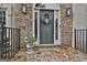Close-up of a home's inviting front door with stone detailing, a wreath, and outdoor lighting at 604 Magnolia Ln, Peachtree City, GA 30269