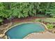 An in-ground pool is surrounded by stone trim and lush landscaping in a backyard with mature trees at 604 Magnolia Ln, Peachtree City, GA 30269