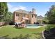 Backyard showing the home's tan vinyl siding, brick chimney, pool, patio, seating area, and landscaping at 6317 Benbrooke Nw Overlook, Acworth, GA 30101