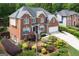 Front exterior featuring brick, a large front yard with mature landscaping, and an attached two-car garage at 6317 Benbrooke Nw Overlook, Acworth, GA 30101