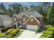 Exterior shot of a brick home with large front yard featuring colorful landscaping, a two-car garage, and a covered porch at 6317 Benbrooke Nw Overlook, Acworth, GA 30101