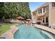 Wide shot of backyard pool with stone surround, lounge chairs, and seating with home's tan vinyl siding at 6317 Benbrooke Nw Overlook, Acworth, GA 30101