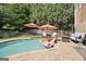Backyard pool area with a stone patio, umbrellas, lounge chairs, and seating area; surrounded by mature trees and landscaping at 6317 Benbrooke Nw Overlook, Acworth, GA 30101